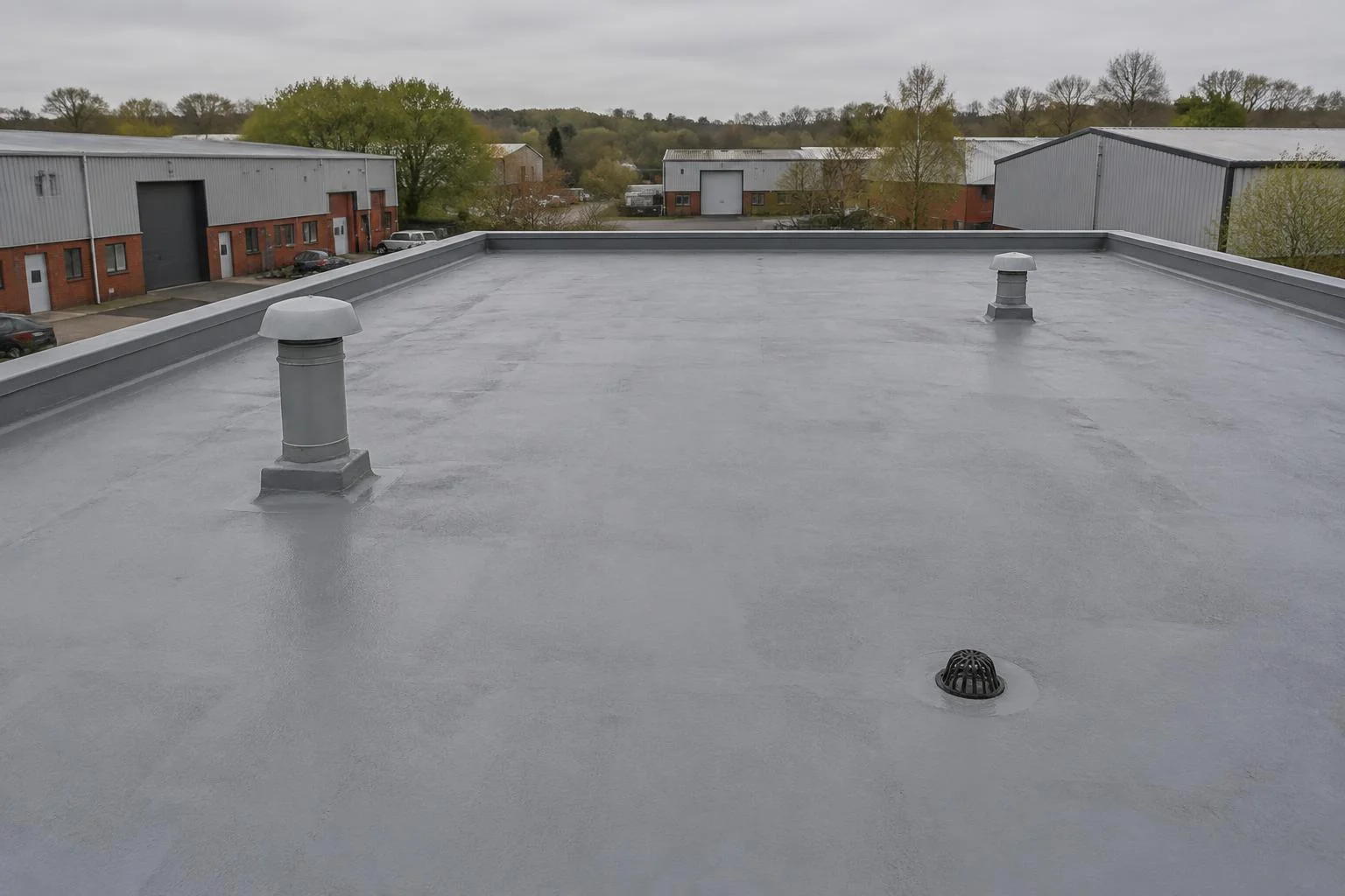 Grey seamless commercial flat roof with vents on a British industrial estate. AI-generated illustration, not an LMB project.